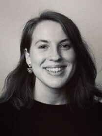 Anja Wenger in Schwarzweiß, lächelnd, mit Ohrring und dunklem Haar.