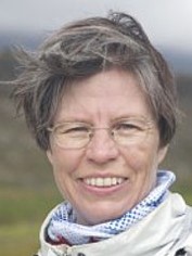 Porträtfoto von Johanna Erdmenger im Freien mit Schal und Brille, freundlich lächelnd.